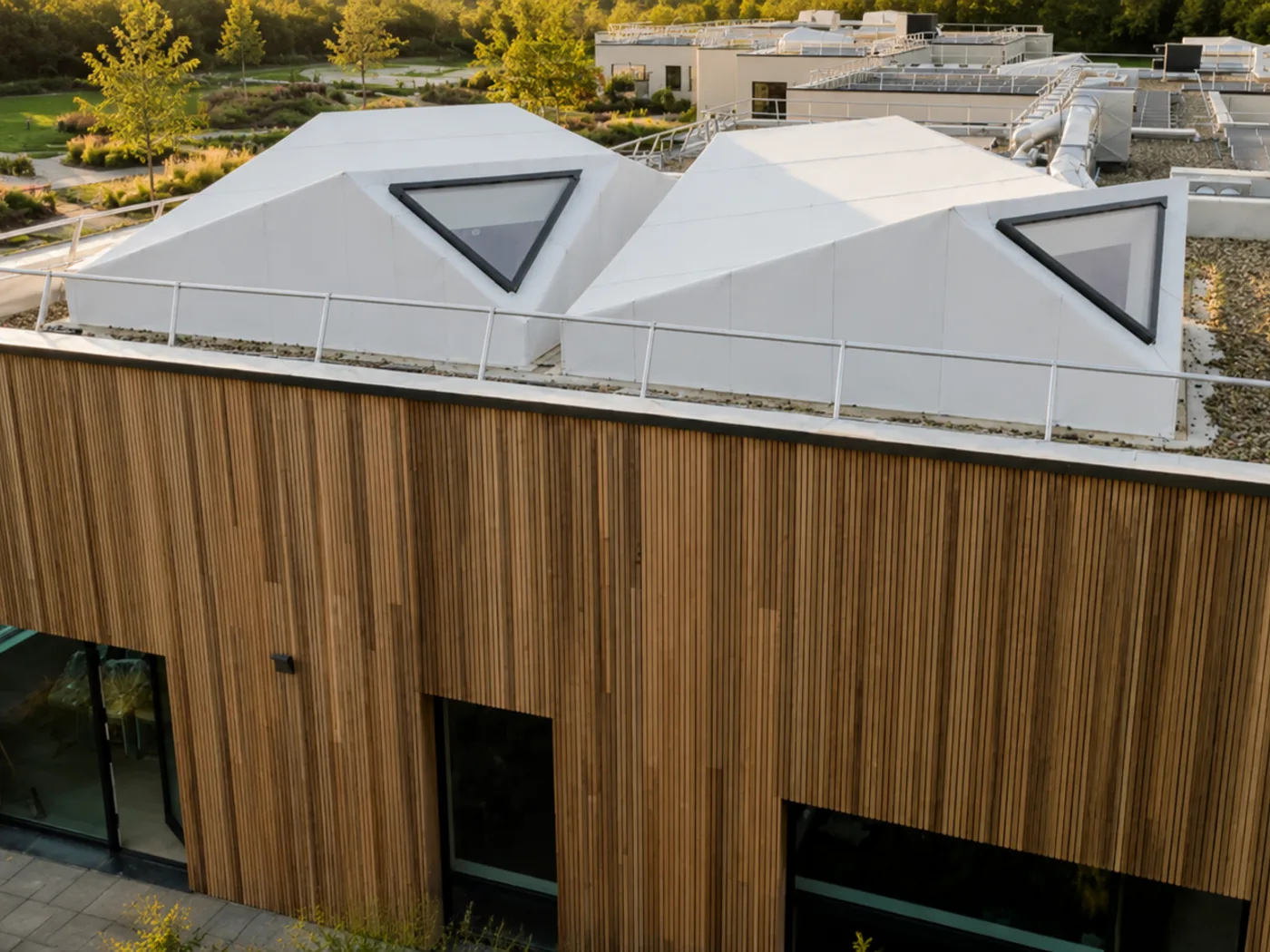 Vue d’ensemble du bâtiment en U autour d’un jardin central, avec toitures végétalisées et lanterneaux pyramidaux.